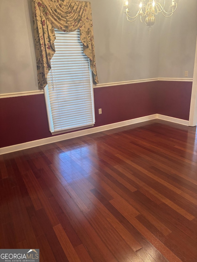 unfurnished room featuring hardwood / wood-style flooring and an inviting chandelier