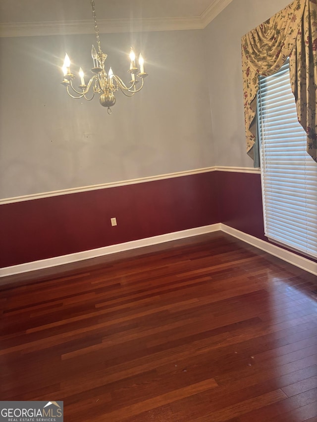 spare room featuring a notable chandelier, crown molding, and hardwood / wood-style flooring