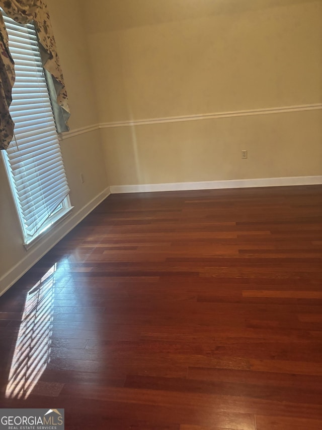 spare room with dark wood-type flooring and plenty of natural light