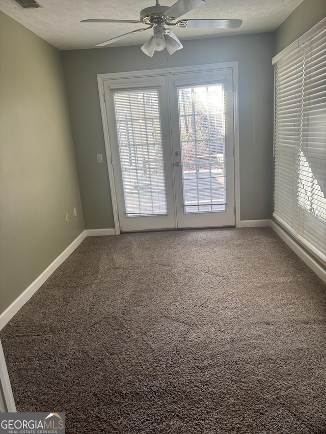 interior space featuring a textured ceiling, carpet floors, ceiling fan, and baseboards