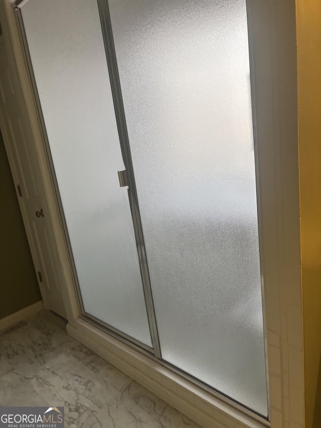 full bathroom featuring marble finish floor and a shower stall