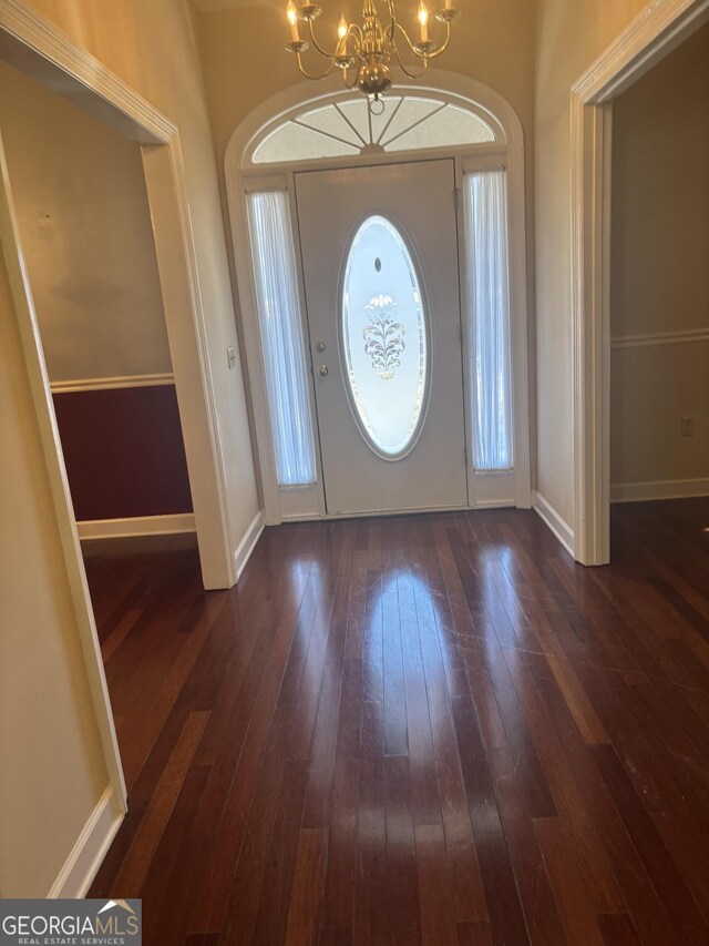 entryway featuring an inviting chandelier, a healthy amount of sunlight, and dark wood-type flooring