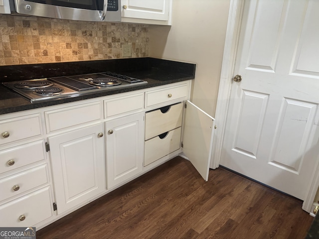 kitchen with dark wood-style flooring, white cabinetry, appliances with stainless steel finishes, decorative backsplash, and dark countertops