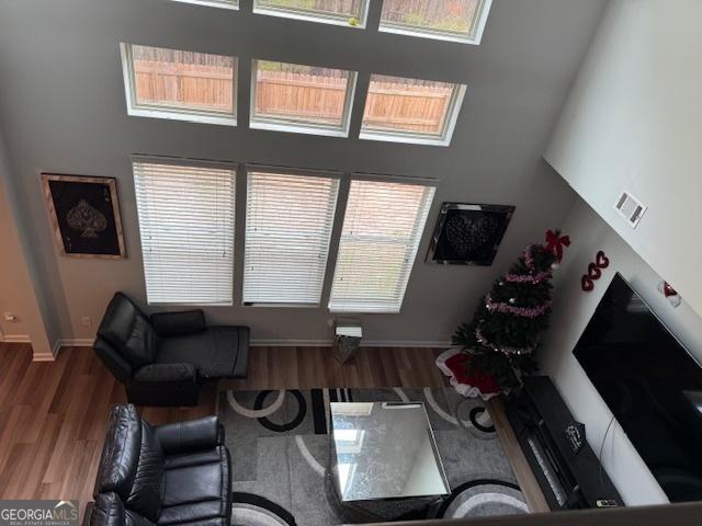 living room with a towering ceiling and wood-type flooring