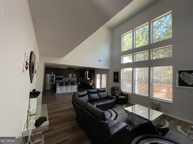 living room with dark hardwood / wood-style floors, a wealth of natural light, and a towering ceiling