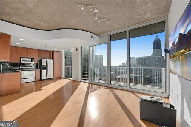 interior space featuring floor to ceiling windows, sink, and light hardwood / wood-style floors