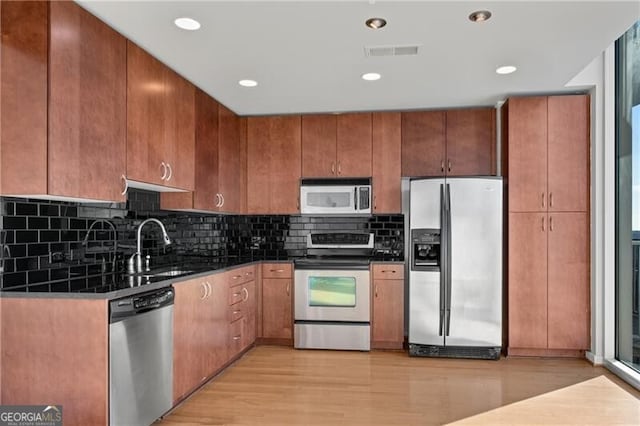 kitchen with tasteful backsplash, sink, stainless steel appliances, and light wood-type flooring