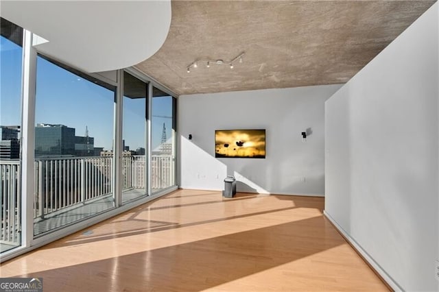 empty room with a wall of windows, wood-type flooring, and plenty of natural light