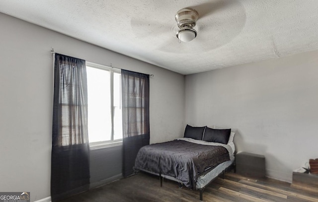 bedroom featuring dark hardwood / wood-style floors, a textured ceiling, and ceiling fan