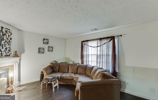 living room featuring a fireplace, dark wood-type flooring, and a textured ceiling