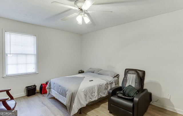 bedroom featuring multiple windows, ceiling fan, and light wood-type flooring