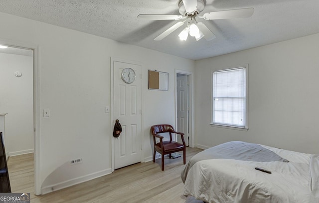 bedroom with a textured ceiling, light hardwood / wood-style flooring, and ceiling fan