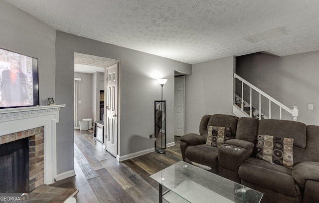 living room with dark hardwood / wood-style flooring, a fireplace, and a textured ceiling