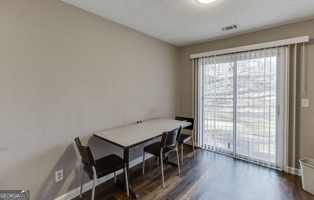 dining space with dark wood-type flooring and a textured ceiling