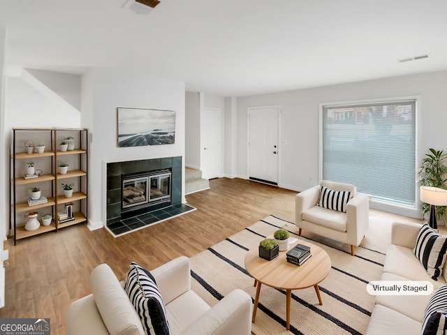 living room with a tiled fireplace and light hardwood / wood-style floors