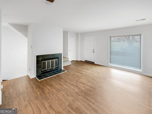 unfurnished living room featuring hardwood / wood-style flooring and a tile fireplace