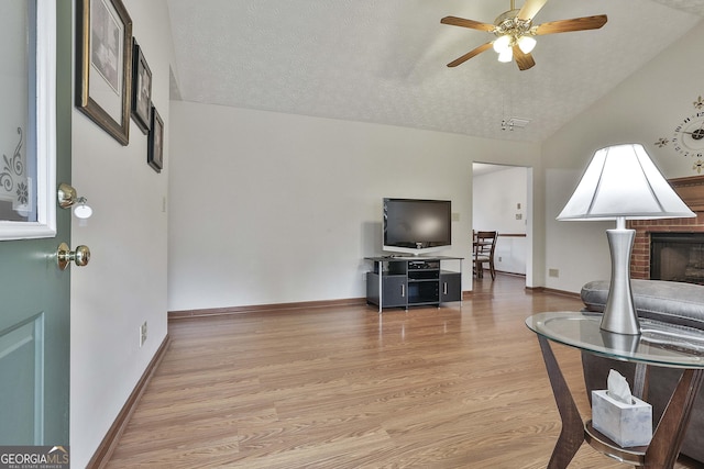 living room featuring ceiling fan, lofted ceiling, a textured ceiling, and light hardwood / wood-style flooring