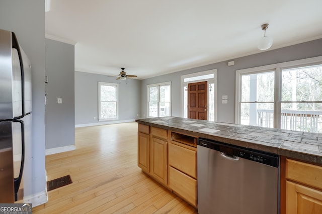 kitchen with ceiling fan, appliances with stainless steel finishes, tile counters, and light wood-type flooring