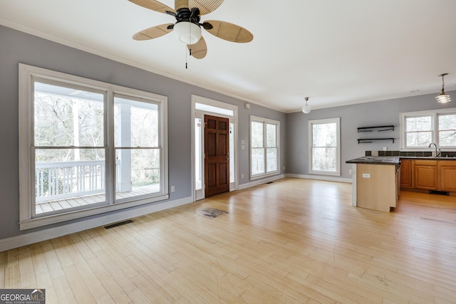 kitchen featuring sink, a breakfast bar area, crown molding, ceiling fan, and light hardwood / wood-style floors