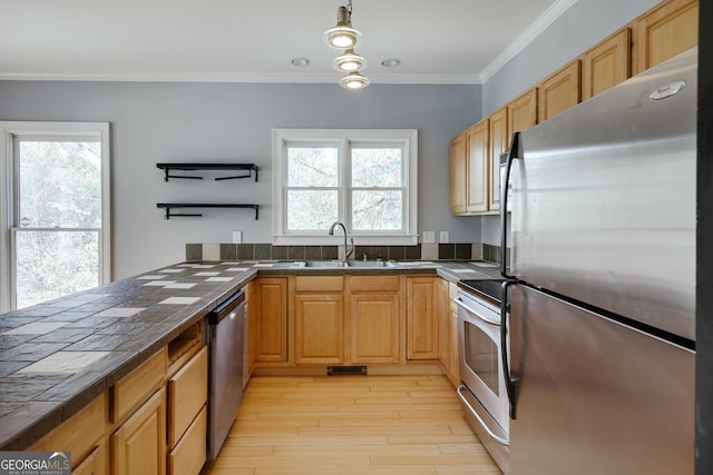 kitchen with sink, crown molding, tile countertops, pendant lighting, and stainless steel appliances