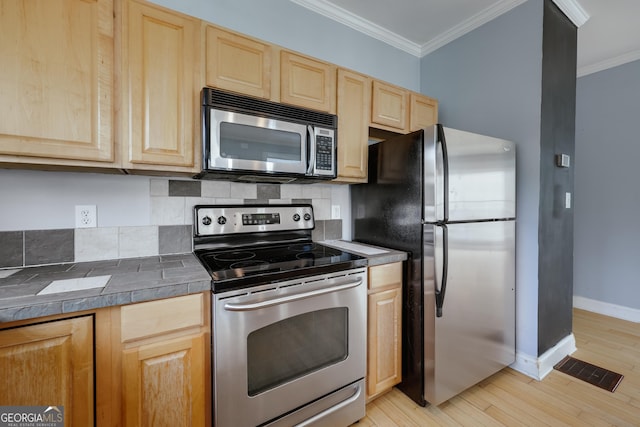 kitchen with ornamental molding, appliances with stainless steel finishes, and light brown cabinets