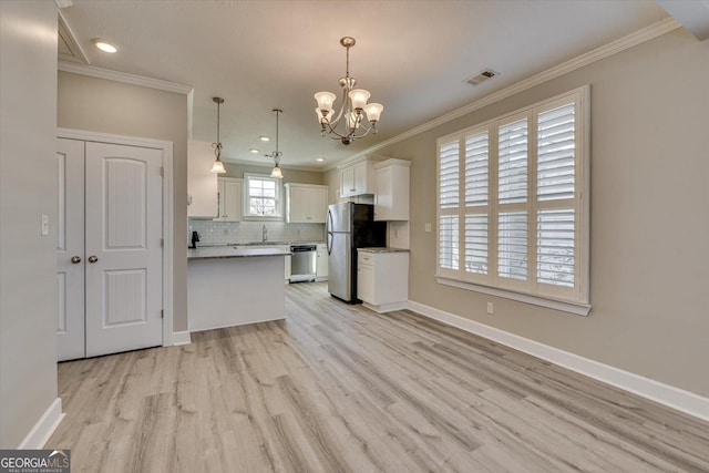 kitchen with hanging light fixtures, ornamental molding, appliances with stainless steel finishes, white cabinets, and backsplash