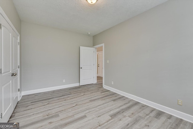 unfurnished bedroom featuring a textured ceiling and light hardwood / wood-style flooring