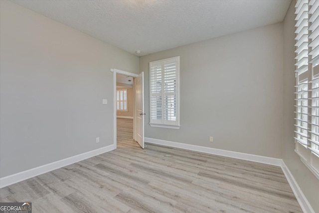 unfurnished room with light hardwood / wood-style flooring and a textured ceiling