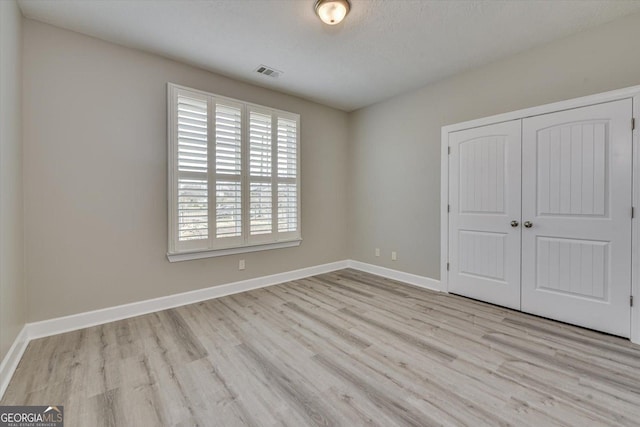 unfurnished bedroom with a closet and light hardwood / wood-style flooring