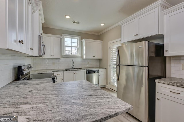 kitchen featuring sink, crown molding, appliances with stainless steel finishes, white cabinetry, and backsplash