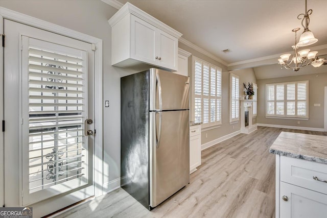 kitchen with decorative light fixtures, stainless steel fridge, and white cabinets