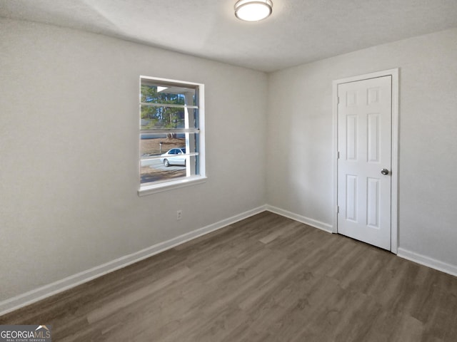 unfurnished room with dark wood-type flooring