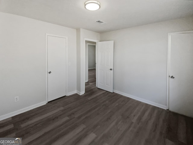 unfurnished bedroom with dark hardwood / wood-style flooring and a closet