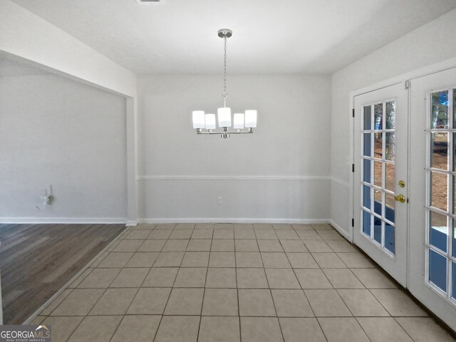 unfurnished dining area featuring french doors, a chandelier, and light tile patterned floors