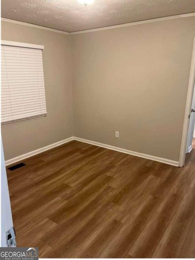 empty room with crown molding, dark wood-type flooring, and a textured ceiling