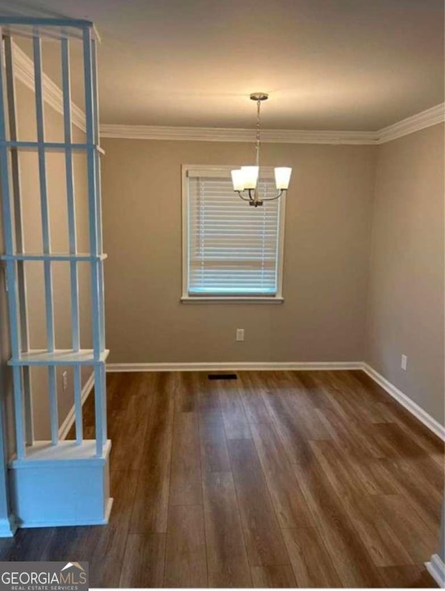 empty room with an inviting chandelier, dark hardwood / wood-style flooring, and crown molding