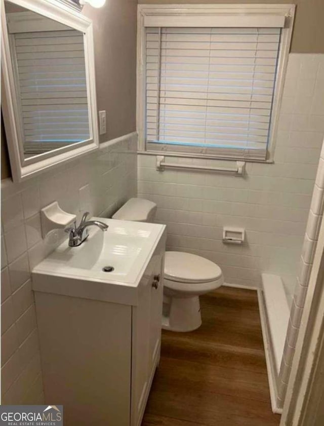 bathroom featuring tile walls, hardwood / wood-style floors, vanity, and toilet