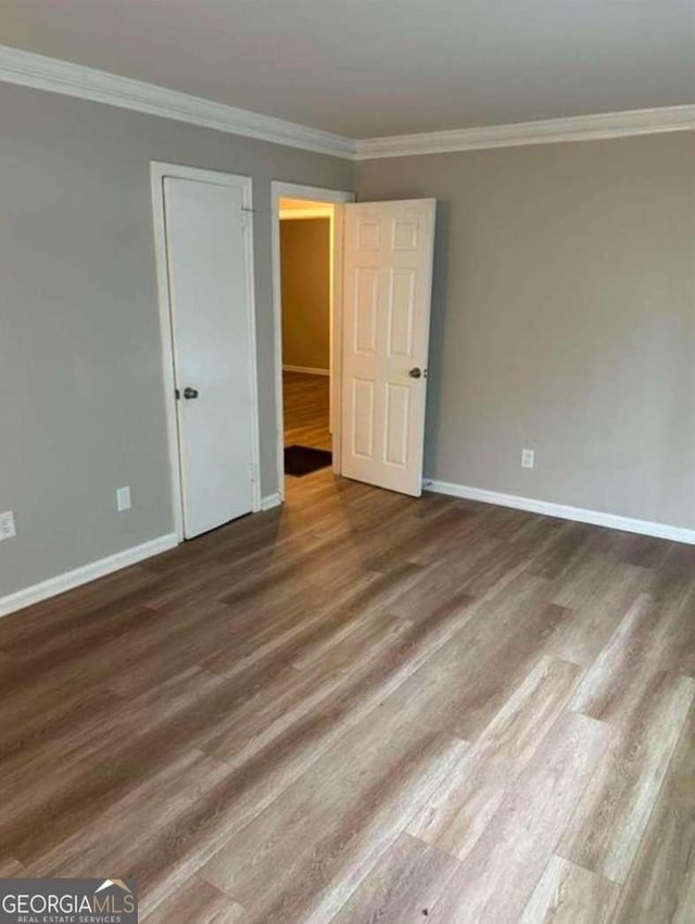 empty room with hardwood / wood-style floors and crown molding