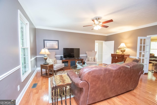 living room featuring plenty of natural light, ornamental molding, and light hardwood / wood-style floors