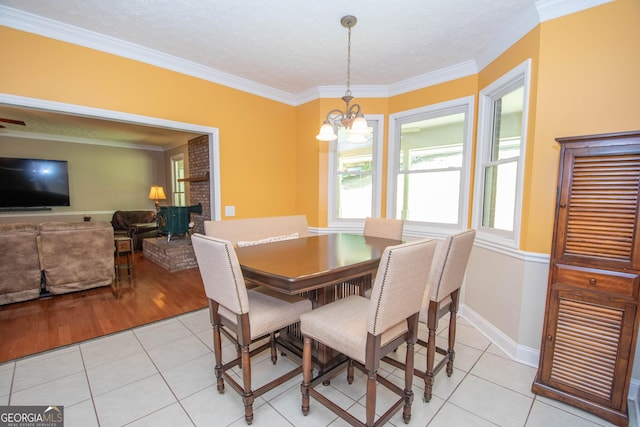 dining space with light tile patterned floors, crown molding, a chandelier, and a textured ceiling