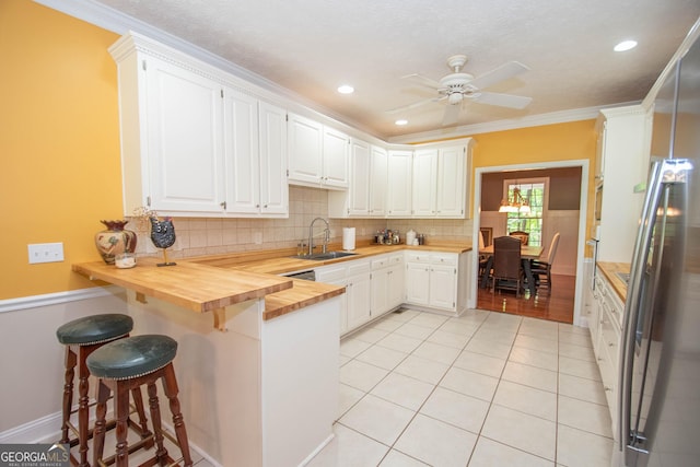 kitchen featuring stainless steel refrigerator, sink, white cabinets, and butcher block countertops