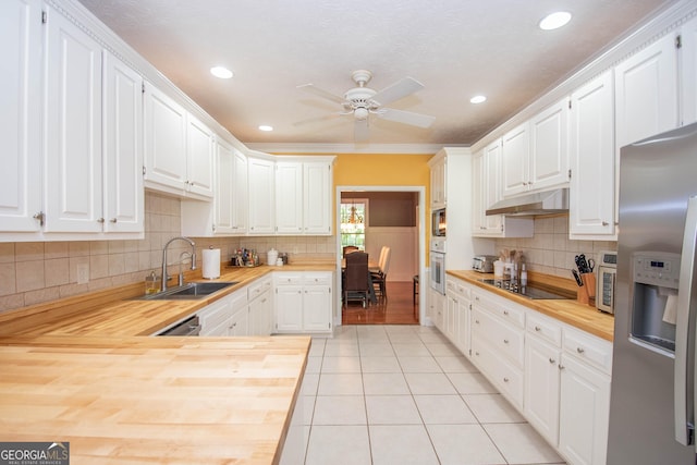 kitchen featuring stainless steel fridge, white cabinetry, butcher block counters, black electric cooktop, and oven