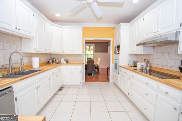 kitchen featuring butcher block countertops, sink, oven, white cabinets, and black electric cooktop