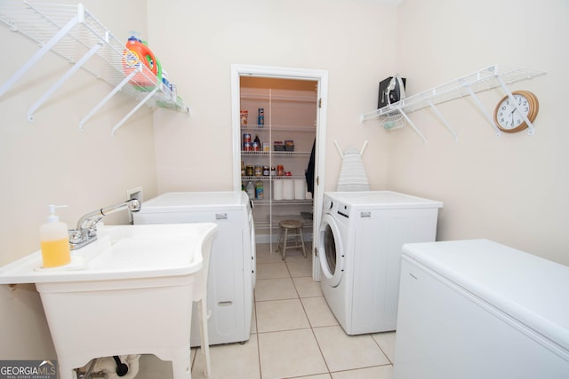 laundry area featuring light tile patterned flooring, washer and dryer, and sink