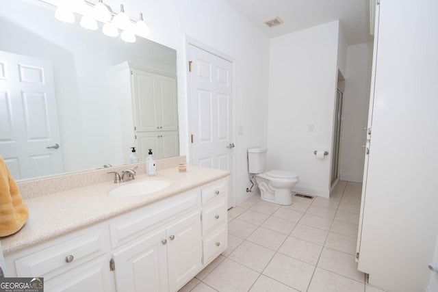 bathroom with vanity, a shower with shower door, tile patterned floors, and toilet