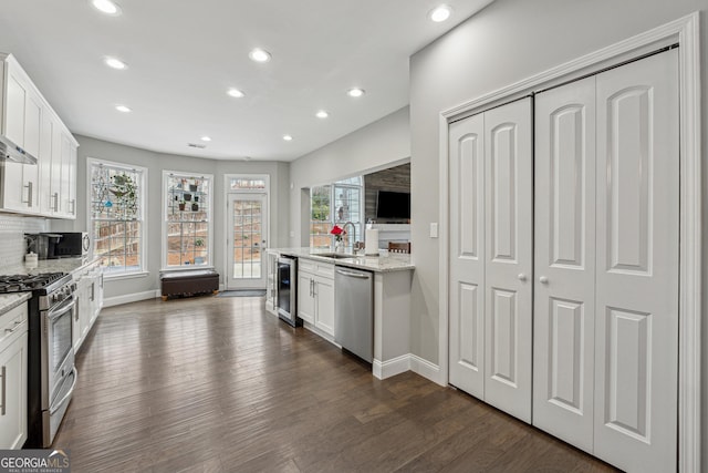 kitchen with stainless steel appliances, wine cooler, white cabinets, and light stone counters