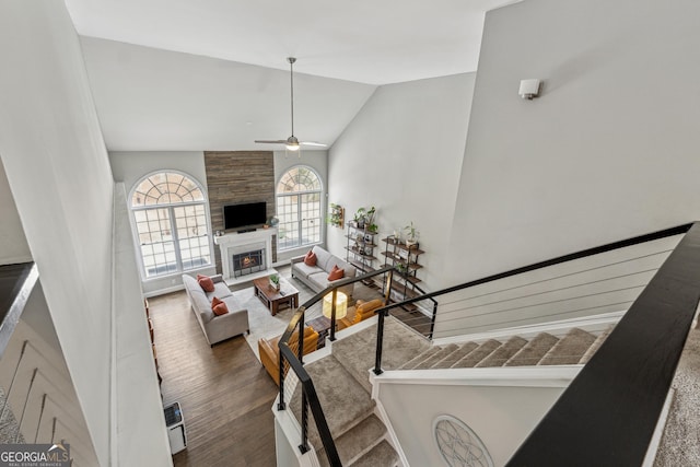 living room featuring ceiling fan, a large fireplace, dark hardwood / wood-style flooring, and vaulted ceiling