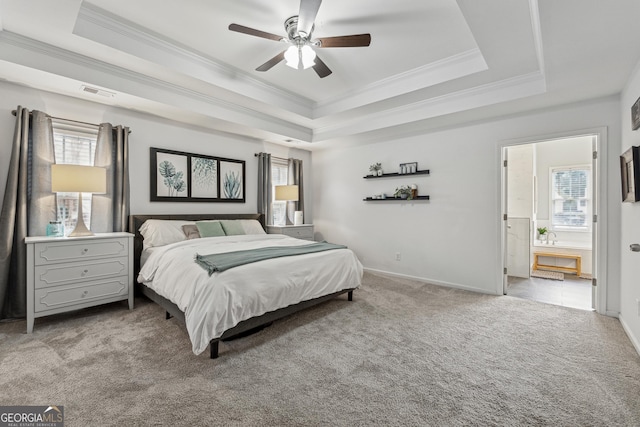 carpeted bedroom featuring ensuite bathroom, ornamental molding, ceiling fan, and a tray ceiling