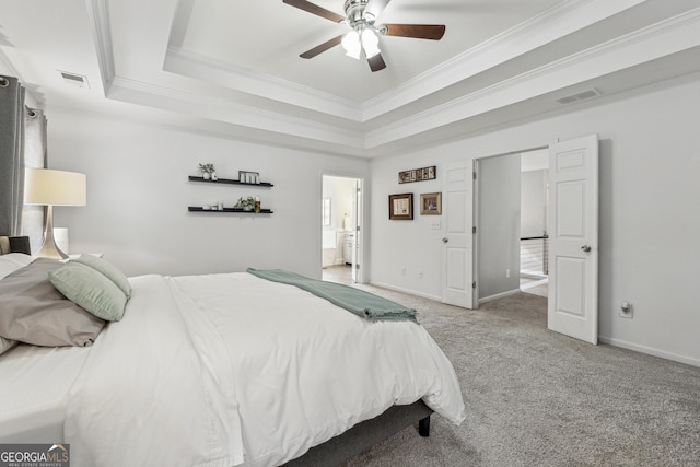 carpeted bedroom featuring ceiling fan, ensuite bathroom, a tray ceiling, and ornamental molding