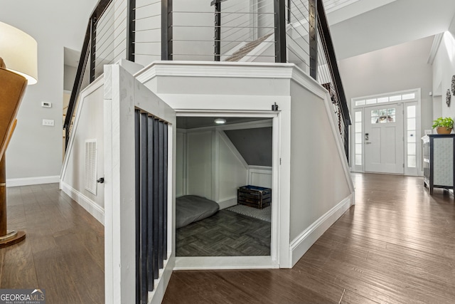 hallway with a towering ceiling and dark hardwood / wood-style floors